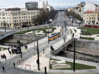 a city street with a bridge and people walking around