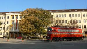 a red train in front of a building