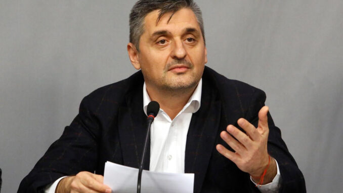 a man sitting at a podium with a microphone